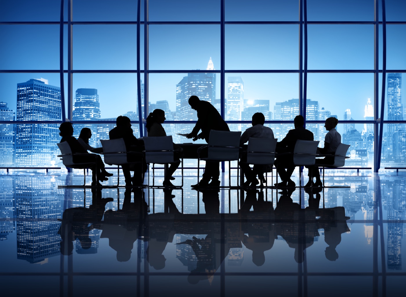 Boardroom meeting silhouetted against a blue city skyline