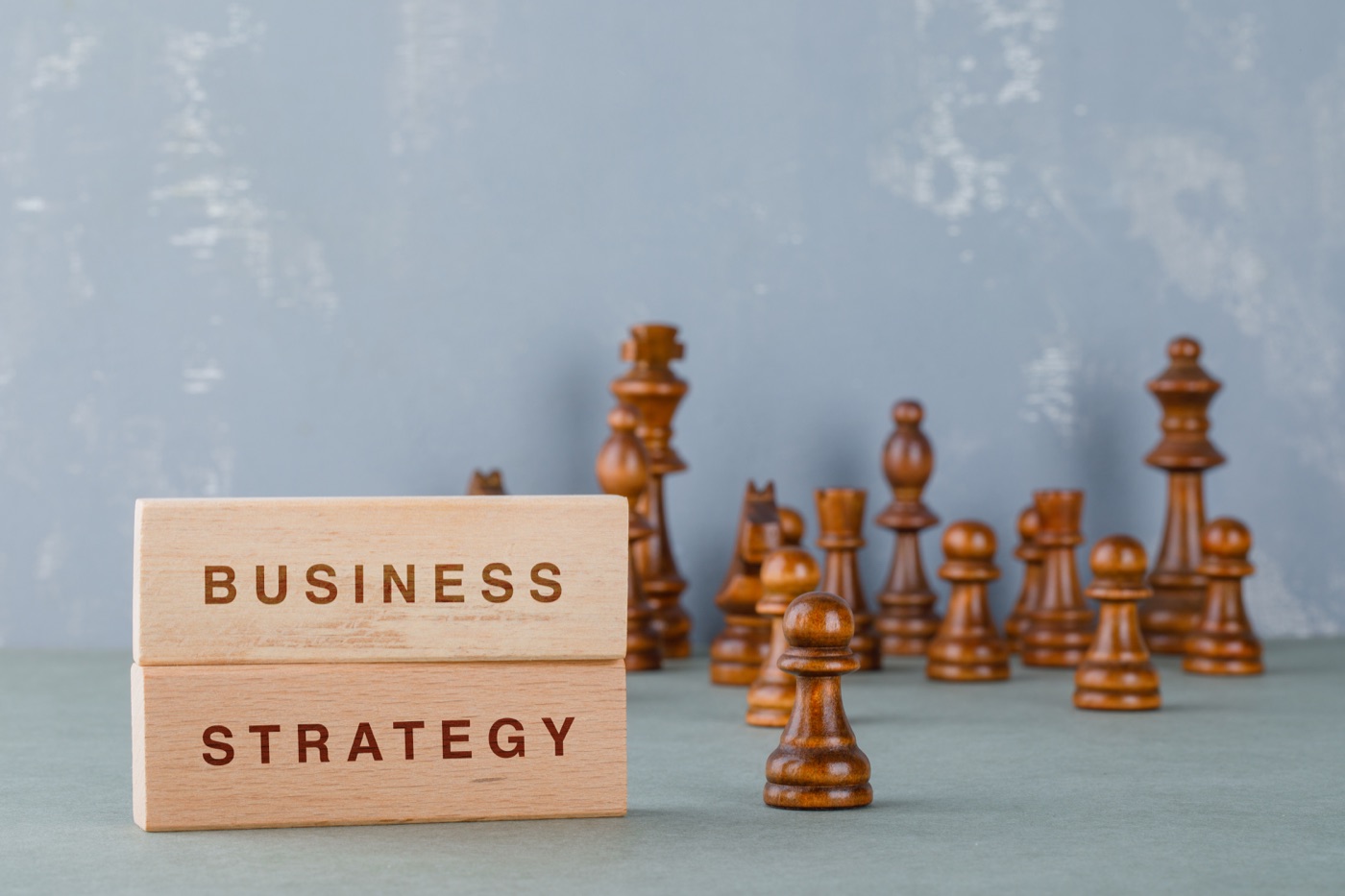 Wooden business strategy blocks beside chess pieces