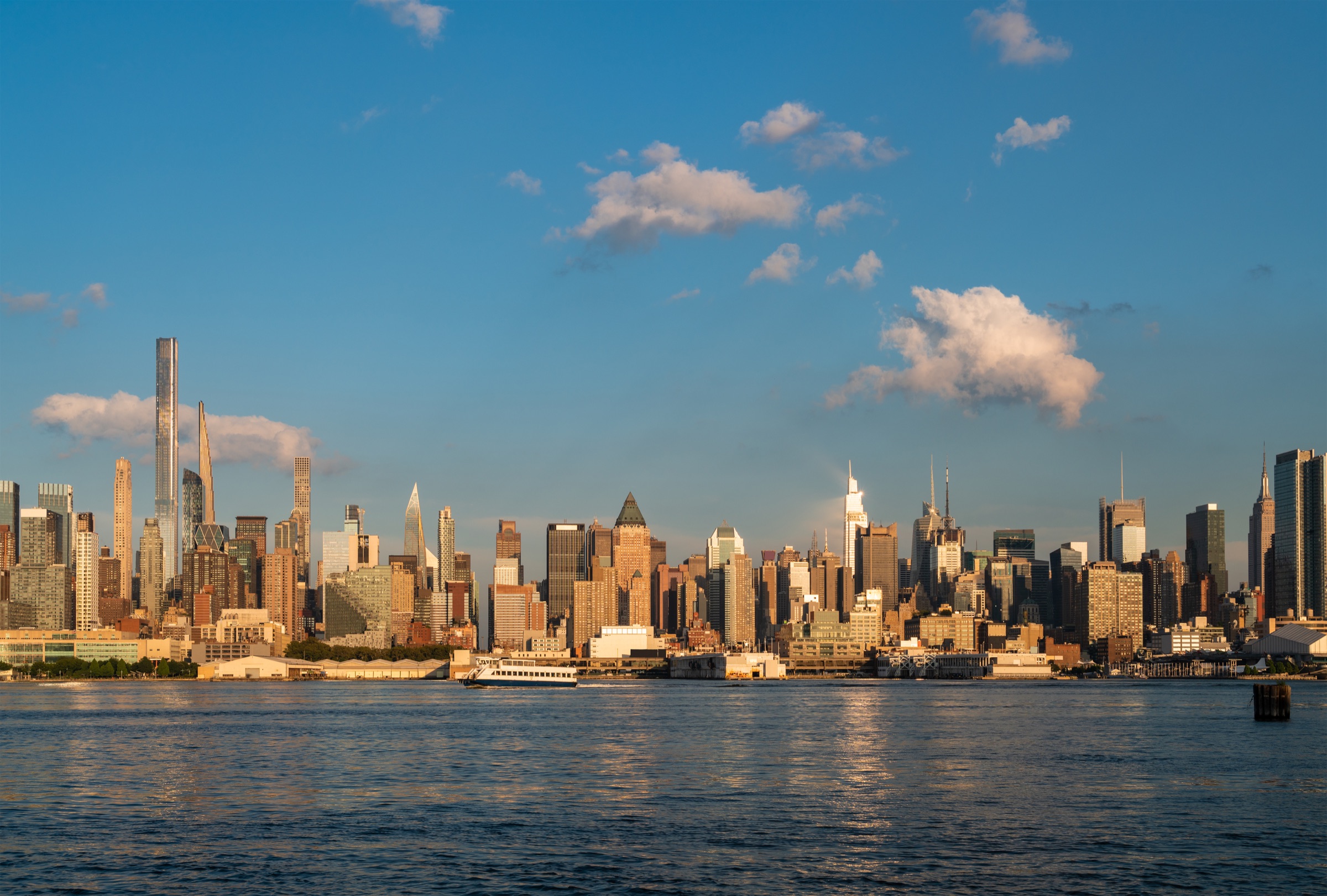 Sunlit Manhattan skyline with a ferry on the Hudson River